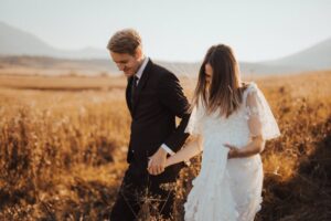 shallow focus photo of man in black formal suit holding woman s hand in white dress