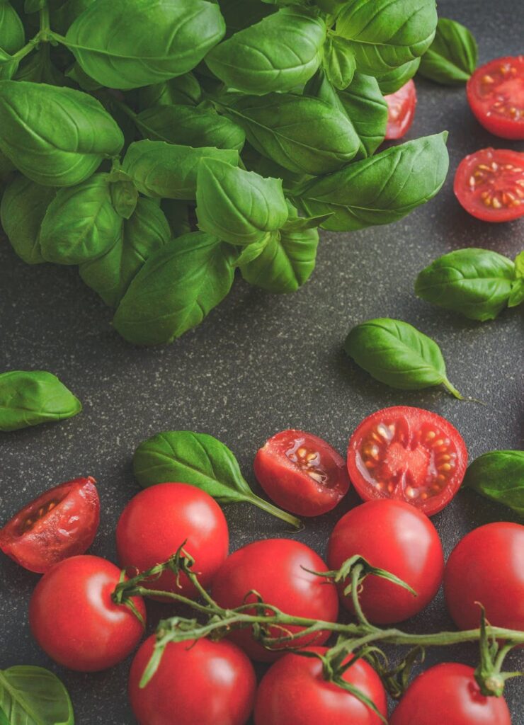 photography of tomatoes near basil leaves