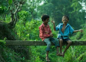 two boys sitting on gray wood plank